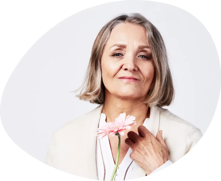 Osteopathie in Hamburg, lächelnde ältere Dame mit rosa Blume